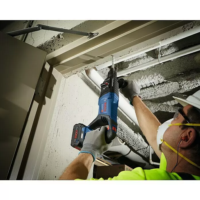 Bosch Professional AMPShare 18V Akku-Kombihammer GBH 18 V-26 D - 18 V, Ohne Akku, 2,5 J - Arbeiter bohrt mit blau-schwarzem Bosch Akku-Bohrhammer und rotem ProCORE 18V Akku in Betondecke.