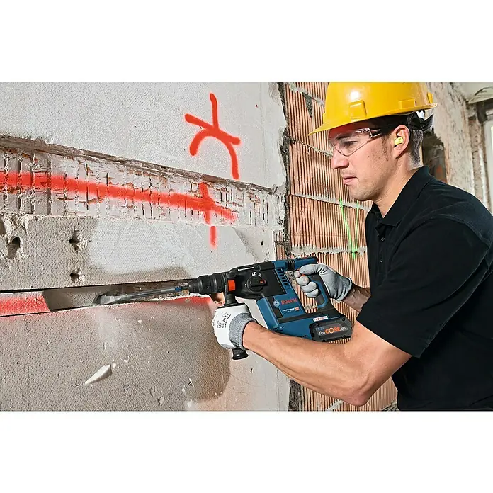 Bosch Professional AMPShare 18V Akku-Kombihammer GBH 18V-26 F - 18 V, 2 Akkus, 5,5 Ah, 2,6 J, Inkl. Staubabsaugung - Bauarbeiter in Arbeitskleidung mit einem Bosch Bohrhammer beim Stemmen einer Wand.