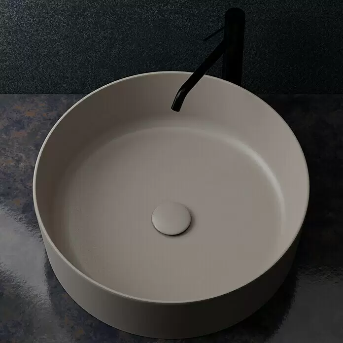 RAK Ceramics Feeling Ablaufventil - 1 ¼″, Cappuccino, Permanent geöffnet - Matt beiges Rundwaschbecken mit schwarzem Wasserhahn auf dunkler, texturierter Ablage.