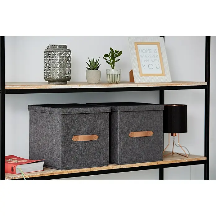 Store It Premium Aufbewahrungsbox - L x B x H: 30 x 30 x 30 cm, Grau - Das Bild zeigt ein Regal mit dekorativen Elementen und zwei grauen Aufbewahrungsboxen mit Deckel und Ledergriffen.