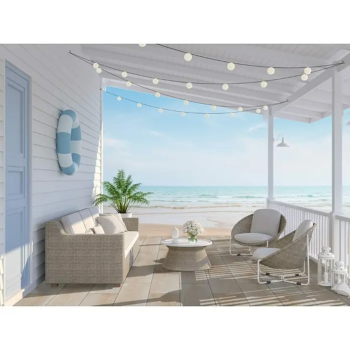 EHL Terrassenplatte Grande - 80 x 40 x 5 cm, Sand, Beton - Einladende Terrasse mit gemütlichen Rattanmöbeln und Blick auf den Strand. Die sanfte Beleuchtung sorgt für eine entspannte Atmosphäre.