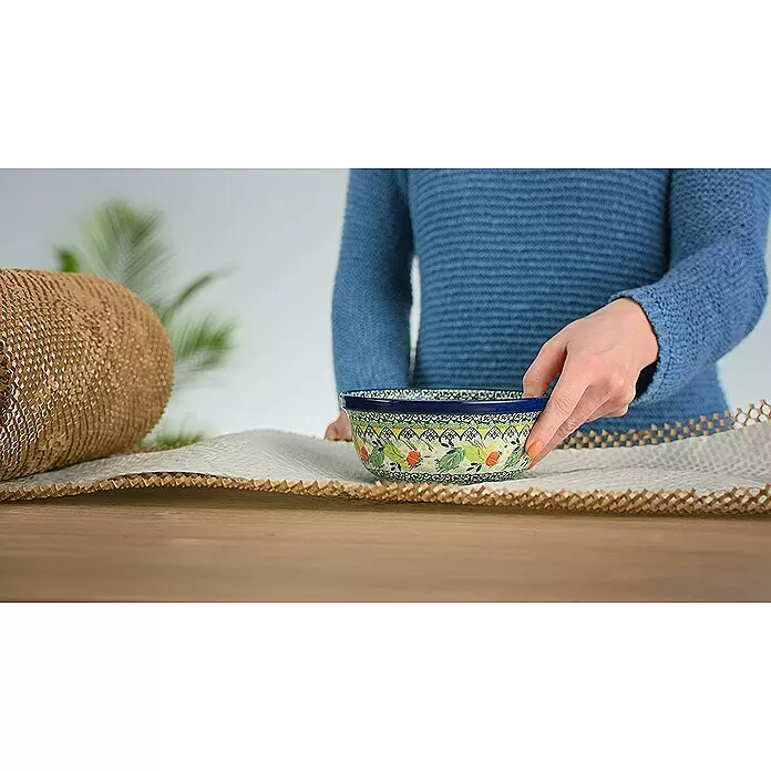 Ranpak Luftpolsterpapier NatureWrap - L x B: 10 m x 35 cm - Hand hält eine gemusterte Keramikschale auf brauner Wabenpapier-Verpackung, neben einer Rolle des Materials.