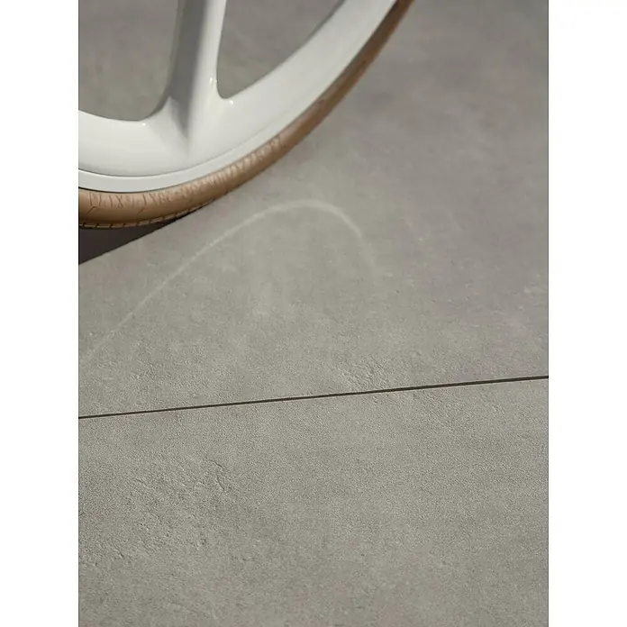 Marazzi Terrassenfliese Esterno 20T Plaster Grey - 60 x 60 x 2 cm, Grau, Matt - Detailaufnahme eines Fahrradreifens mit weißer Felge auf einem grauen Untergrund, der die Textur und das Design hervorhebt.