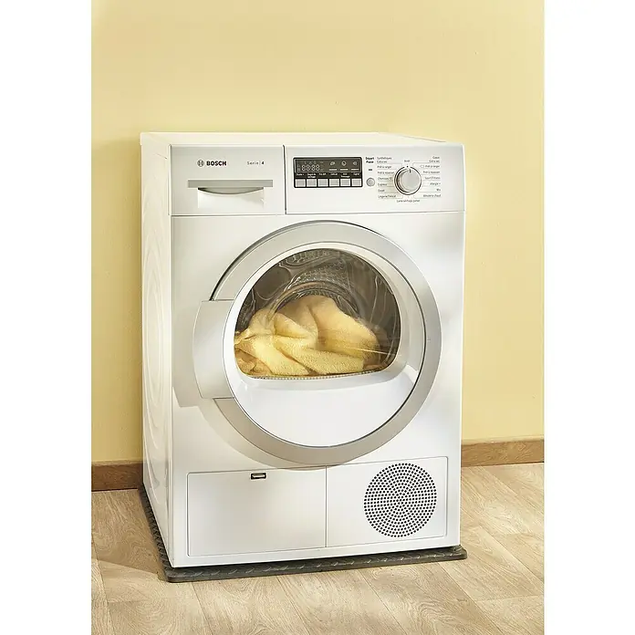 Mottez Vibrationsdämpfungsmatte - Grau - Frontansicht eines Bosch Serie 4 Wäschetrockners in Weiß, der auf einer dunklen Matte steht und mit Wäsche beladen ist.