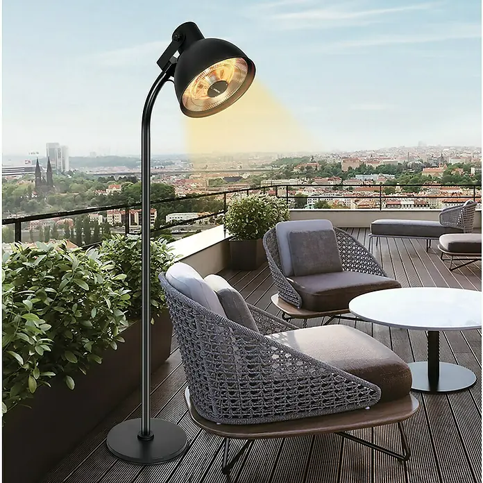 Hoberg Infrarot-Heizstrahler - Schwarz - Terrassenheizer mit warmem Lichtschein steht auf einer Holzterrasse mit Möbeln und Blick auf die Stadt.