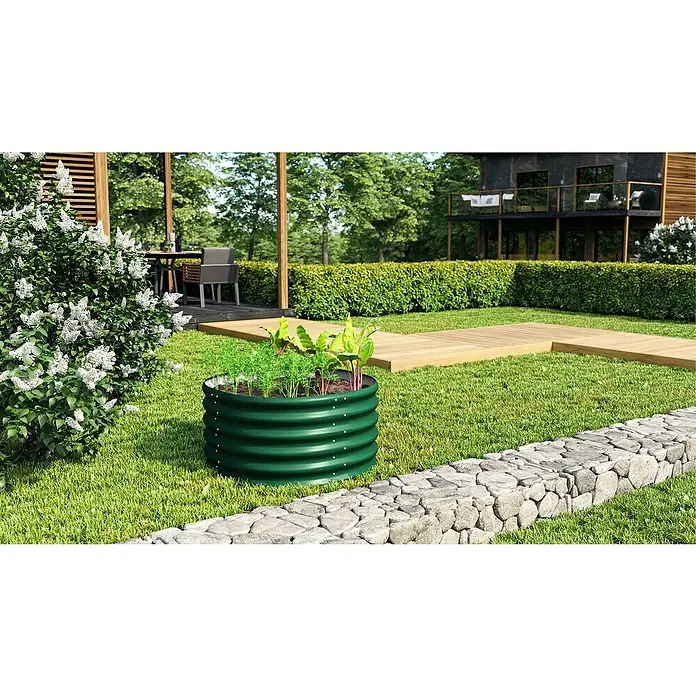 Vitavia Hochbeet Terra 401 - 82 x 82 x 40,1 cm, Zincalume®, Seegras - Gartenlandschaft mit einem grünen, erhöhten Beet, das Gemüse enthält, neben einem Steinwall und blühenden Sträuchern.