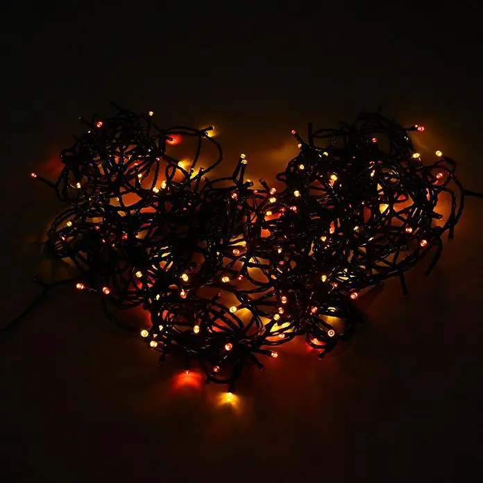 Muvit iO Guirnalda luminosa LED WiFi RGB+CCT - 20 m, RGB, Para interior - Guirnalda de luces en forma de corazón con bombillas rojas y amarillas sobre un fondo oscuro, creando un ambiente cálido y romántico.