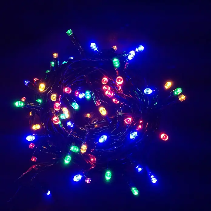 Muvit iO Guirnalda luminosa LED WiFi RGB+CCT - 20 m, RGB, Para interior - Primer plano de un montón de luces LED multicolores iluminadas para el árbol de Navidad, creando un ambiente festivo y alegre.