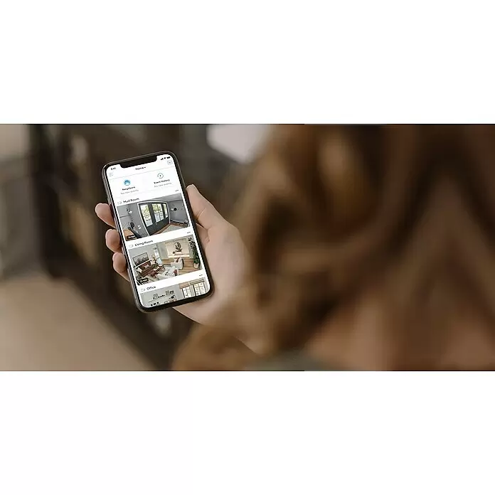 Ring Überwachungskamera außen Stick Up Cam Plug-In - Schwarz, Erfassungswinkel: 110 °, Netzbetrieben - Eine Person hält ein Smartphone, das eine Smart-Home-App mit Live-Kamera-Feeds aus verschiedenen Räumen und Ereignisverlauf anzeigt.