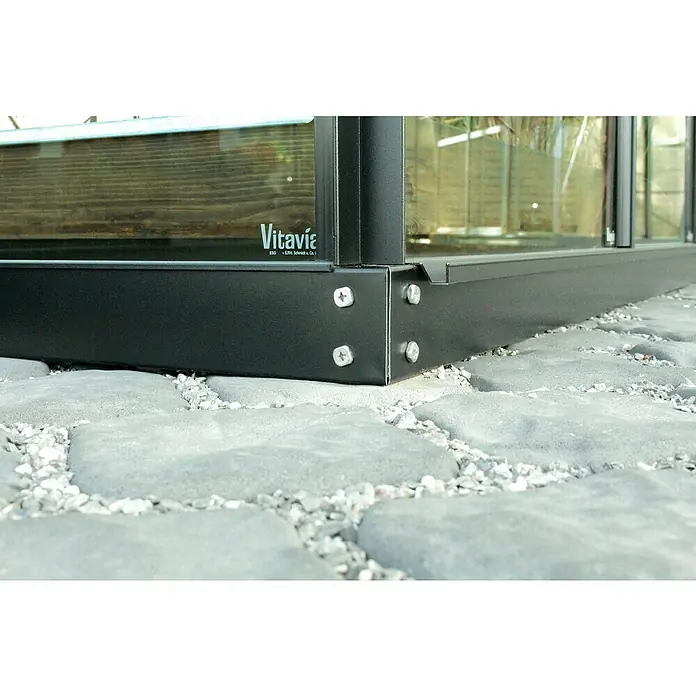 Vitavia Fundament192,2 x 65,3 x 6 cm, Schwarz - Detailaufnahme einer Vitavia Gewächshausbasis, die mit Schrauben auf einem Steinsockel befestigt ist. Robuste und langlebige Konstruktion für den Garten.