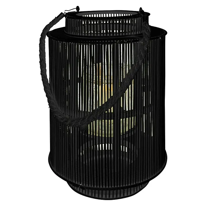 Farolillo alto Pol - Negro, Ø x Al: 27 x 42 cm - Primer plano de una linterna cilíndrica negra con asa de cuerda, que proyecta una cálida luz de vela a través de las lamas.