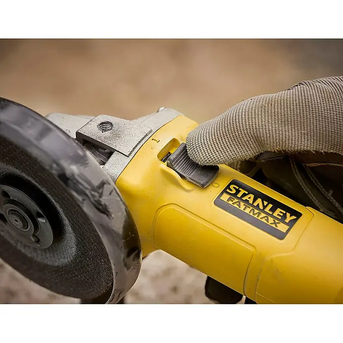 Stanley FatMax Amoladora angular eléctrica FMEG615-QS - 600 W, Diámetro disco: 115 mm, Número de revoluciones de marcha en vacío: 12.000 r.p.m. - Primer plano de una amoladora angular amarilla Stanley Fatmax operada por una mano con guantes de trabajo.