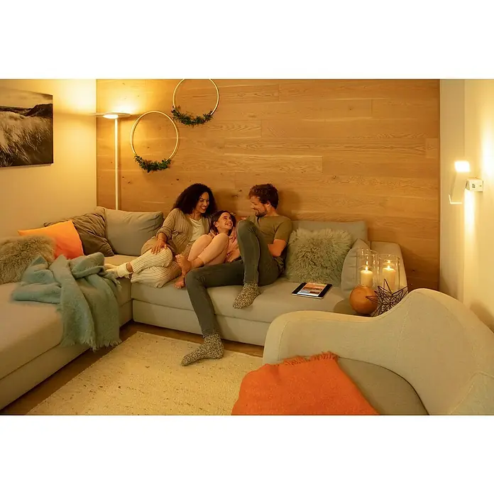 Ledvance SUN@Home LED-Stehleuchte Panan - 36 W, Höhe: 180 cm, Weiß, Kaltweiß - Eine Familie entspannt sich im gemütlichen Wohnzimmer, das durch moderne Lampen und sanfte Farben eine angenehme Atmosphäre erhält. Die Beleuchtung betont die Holzvertäfelung.