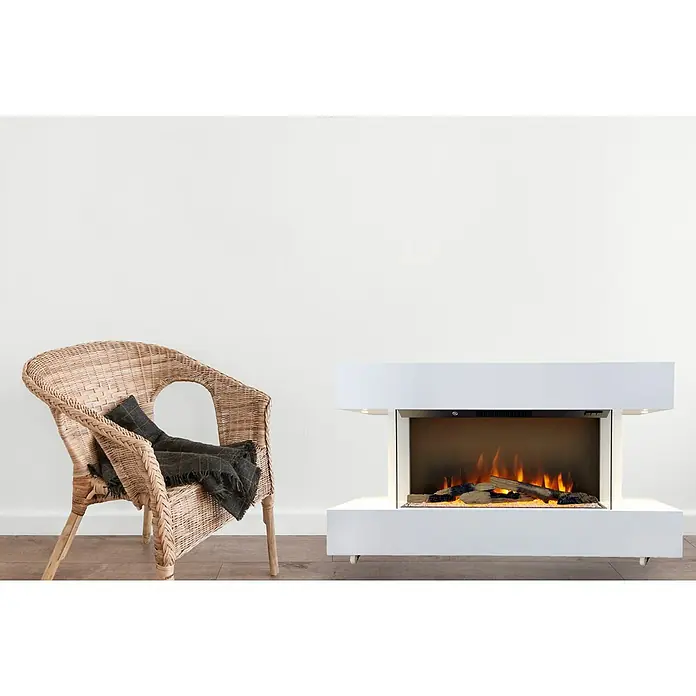 Voltomat HEATING Elektrischer Kamin Göteborg - 1.500 W, Weiß, 26,4 x 120 x 65 cm - Nahaufnahme eines weißen elektrischen Kamin neben einem Korbstuhl mit einer dunklen Decke, die eine gemütliche Atmosphäre erzeugt.
