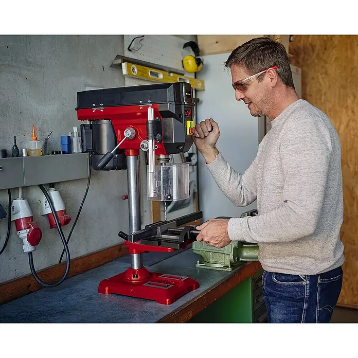 Einhell Tischbohrmaschine TE-BD 550 E - 450 W, Spannweite Bohrfutter: 0 mm - 13 mm - Ein Mann bedient eine rote Tischbohrmaschine in einer Werkstatt, die sich durch Robustheit und Präzision auszeichnet.