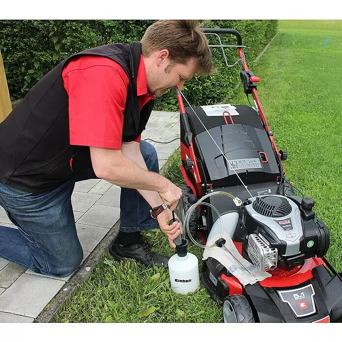 Einhell Druck- & Saugspritze - Tankvolumen: 1,6 l, 16,7 x 15,5 x 21 cm - Mann entleert mit einer Einhell Ölabsaugpumpe Altöl aus einem Rasenmäher in eine weiße Auffangflasche.