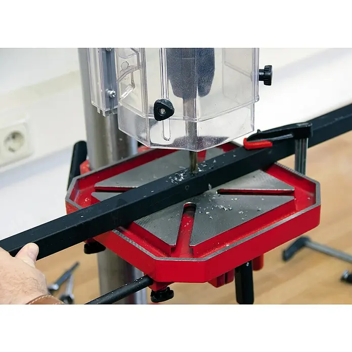 Einhell Tischbohrmaschine TE-BD 750 E - 750 W, 450 U/min - 2.500 U/min - Der Bohrtisch mit einer schwarzen Metallstange wird mit einer Bohrmaschine bearbeitet. Die Tischbohrmaschine hat einen roten Sockel.