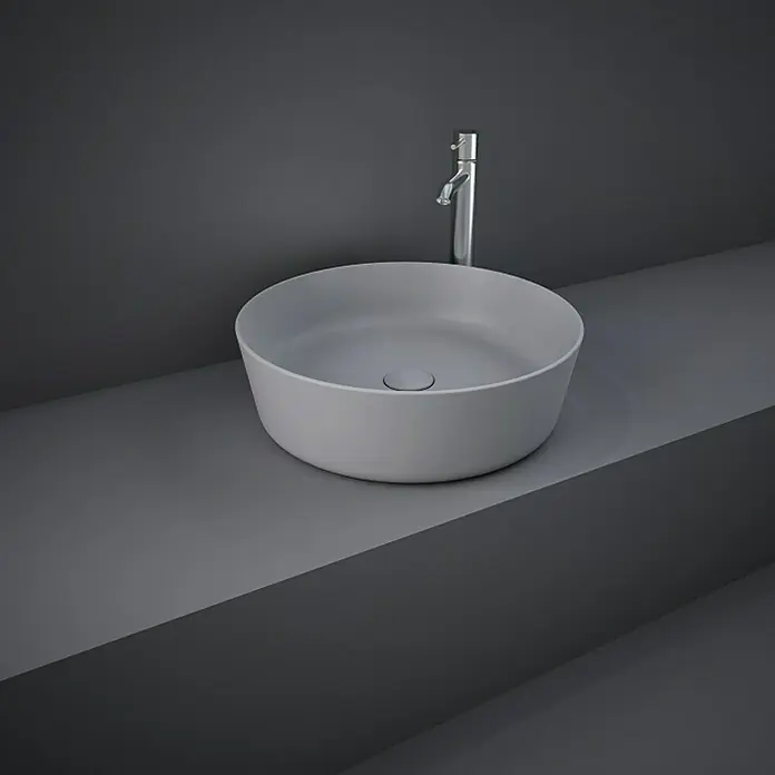 RAK Ceramics Feeling Aufsatzwaschbecken - Durchmesser: 42 cm, Ohne Spezialglasur, Hahnloch: Ohne, Ohne Überlauf, Grau, Matt - Graues Waschbecken mit Armatur. Das Waschbecken ist rund und steht auf einer grauen Ablage, die zur Wand passt, für ein minimalistisches Design.