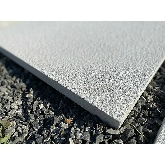 BHS Mallorca Pavimento losa - L x An: 70 x 35 cm, Gris - Primer plano de una losa de piedra gris claro con una superficie rugosa sobre un lecho de grava oscura.