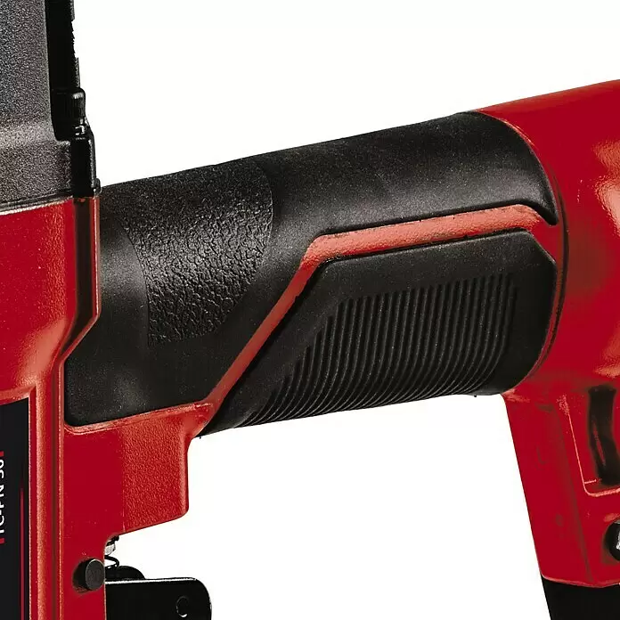 Einhell Drucklufttacker TC-PN 50 - Betriebsdruck: 8,3 bar, Magazinkapazität: 100 Nägel/Klammern - Nahaufnahme eines roten Elektrowerkzeugs mit schwarzem, strukturiertem, ergonomischem Griff mit gerippten Griffbereichen.