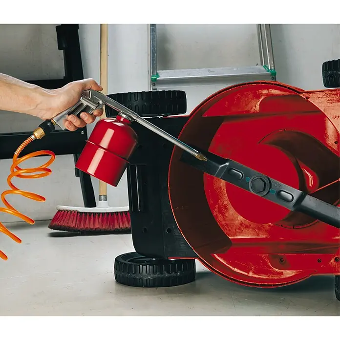 Einhell Sprühpistole mit Saugbecher - Betriebsdruck: 3 bar - 8 bar, Geeignet für: Kompressor - Nahaufnahme eines Rasenmähers, der mit einer Spritzpistole und Druckluft gereinigt wird, um Sauberkeit und Wartung zu gewährleisten.