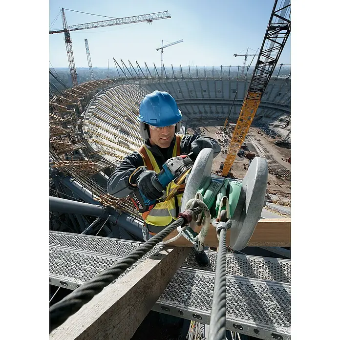 Bosch Professional AMPShare 18V Akku-Winkelschleifer GWX 18V-8 125 mm - Ohne Akku, Durchmesser Scheibe: 125 mm - Arbeiter mit Bosch Winkelschleifer bei Bauarbeiten im Freien, mit Bauhelm und Schutzausrüstung.