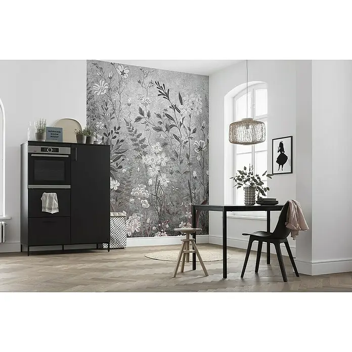Komar Fototapete Moonlight Flowers - B x H: 200 x 250 cm, Vlies - Ein Esszimmer mit einem stilvollen Esstisch und Stuhl, beleuchtet von einer hängenden Lampe, vor einer grauen floralen Wandtapete.