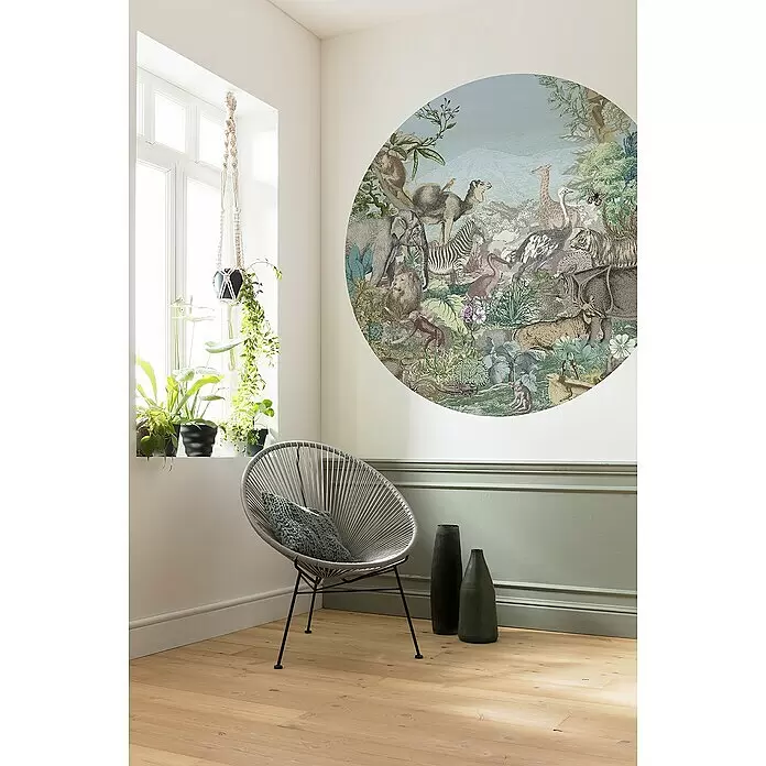 Komar Dots Fototapete rund Animal Kingdom - 128 cm, Selbstklebend - Eine große, runde Wandtapete mit vielfältigen Tieren und üppigem Grün auf einer hellen Wand über einem grauen Stuhl.