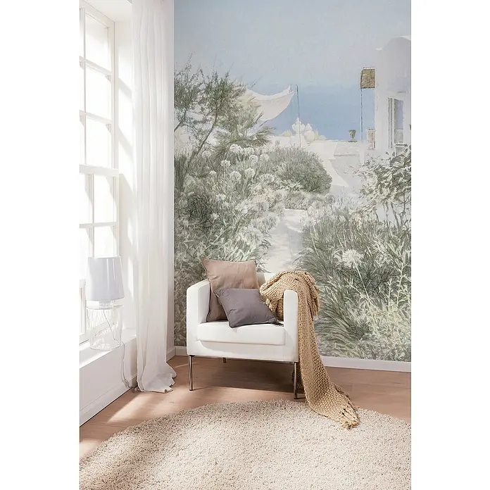 Komar Fototapete Côte d'Azur - B x H: 200 x 250 cm, Vlies - Stilvolles Interieur mit weißem Sessel, dekorativen Kissen und einer gemütlichen Strickdecke auf einem flauschigen Teppich vor einer mediterranen Wandtapete.