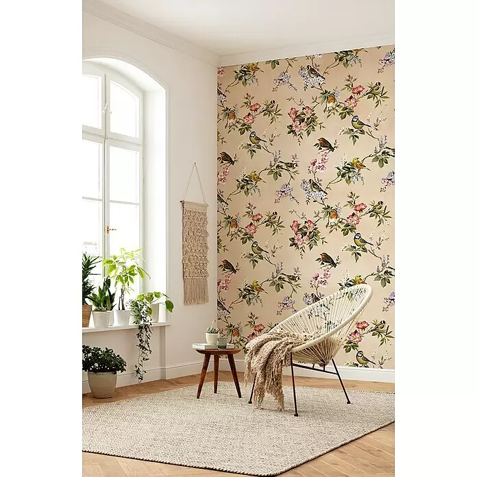 Komar Fototapete Concert De Demain - B x H: 200 x 250 cm, Vlies - Beige Tapete mit lebhaftem Vogel- und Blumenmuster, schmückt eine Wand in einem gemütlichen, sonnigen Raum.