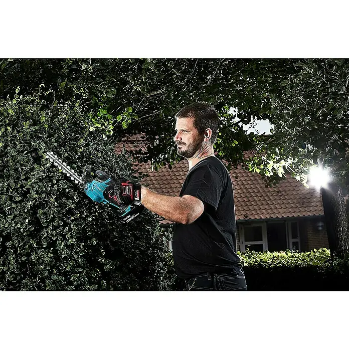 Makita LXT 18V Akku-Gras- & Strauchschere DUM604ZX - 18 V, Li-Ionen, Ohne Akku, Schwertbreite: 16 cm - Ein Mann schneidet eine Hecke mit einer Akku-Heckenschere von Makita, wobei die Schärfe der Klingen und die Leistung des Werkzeugs hervorgehoben werden.