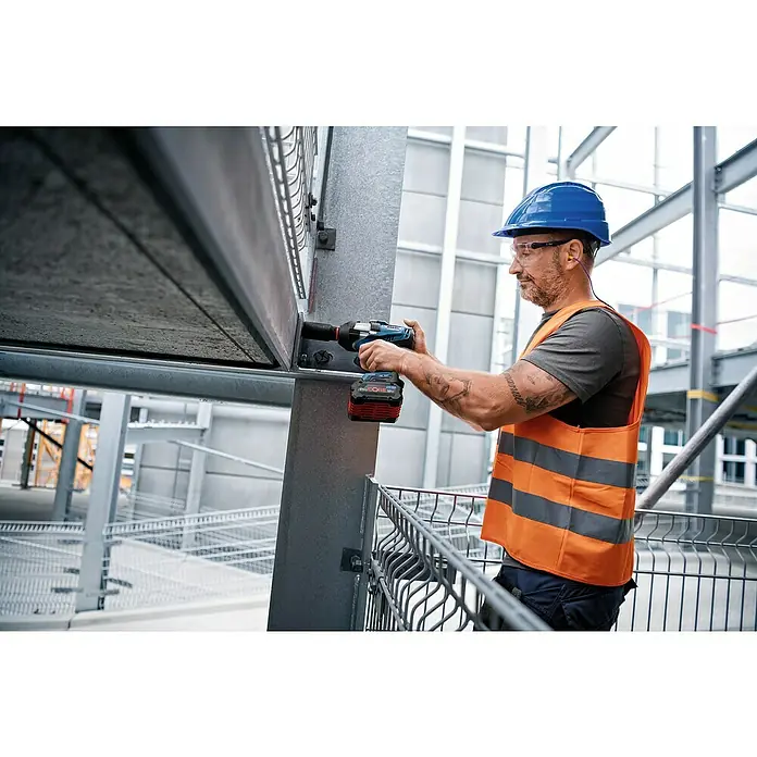 Bosch Professional AMPShare 18V Akku-Drehschlagschrauber GDS 18V-1000 C - 18 V, 2 Akkus, 8 Ah, 1.000 Nm, Inkl. Bluetooth Low Energy Modul GCY 42 - Ein Bauarbeiter befestigt eine Stahlkonstruktion mit einem blauen Bosch-Akkuschlagschrauber. Er trägt Helm, Schutzbrille und Warnweste.