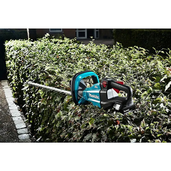 Makita LXT 18V Akku-Heckenschere DUH502Z - 18 V, Li-Ionen, Ohne Akku, Schnittlänge: 50 cm - Akku-Heckenschere von Makita beim Trimmen einer Hecke. Das Gerät ist türkis und schwarz mit einer langen Klinge.