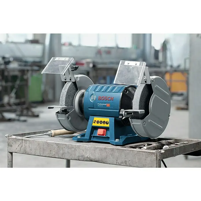 Bosch Professional Elektro-Doppelschleifer GBG 60-20 - 600 W, 3.600 U/min - Nahaufnahme einer Bosch Professional Werkbank Schleifmaschine mit Schleifscheiben, Schutzvorrichtungen und Bedienelementen auf einem Arbeitstisch.