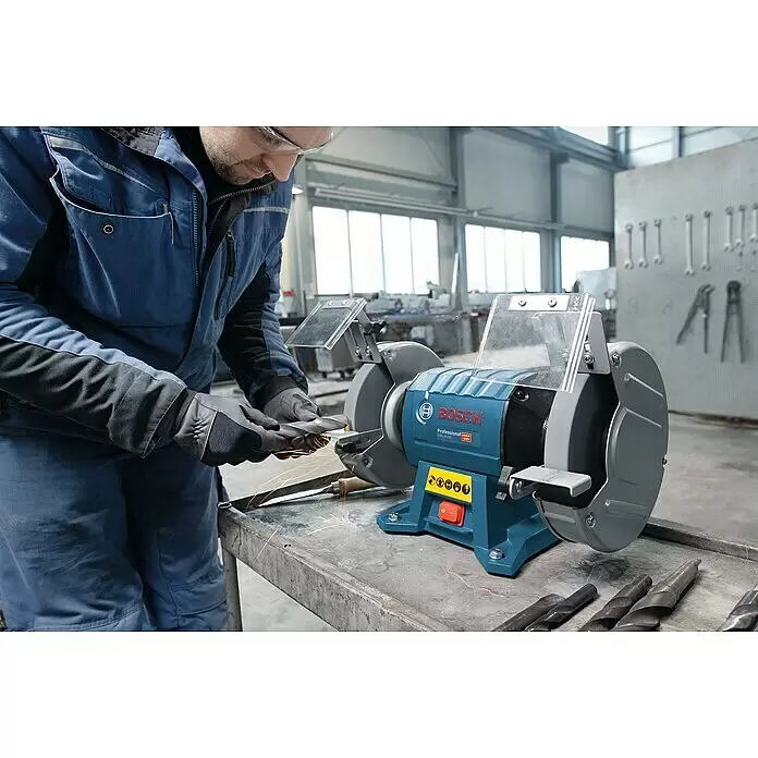 Bosch Professional Elektro-Doppelschleifer GBG 60-20 - 600 W, 3.600 U/min - Eine Person schärft einen Bohrer an einem blau-grauen Bosch Doppelschleifer, Funken sprühen.