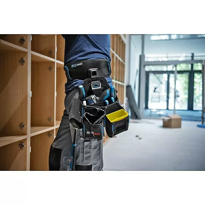 Bosch Professional Werkzeug-Gürteltasche GWT 4 - 210 x 150 x 250 mm - Arbeiter mit schwarzem und blauem Bosch ProClick Werkzeuggürtel, gefüllt mit blauen und schwarzen Hand- und Elektrowerkzeugen auf Baustelle.
