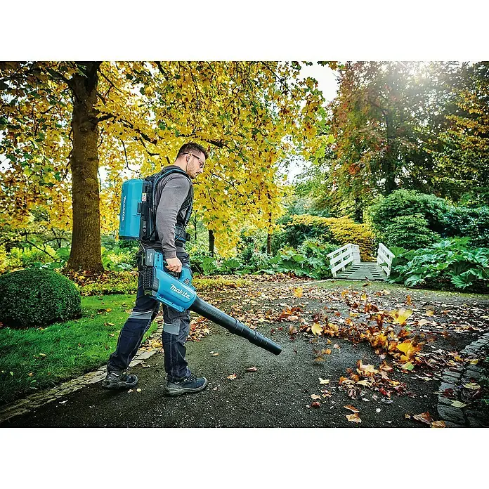 Makita LXT 18V Akku-Gebläse DUB184RF - 18 V, 1 Akku, 3 Ah, Blasgeschwindigkeit: 52,1 m/s - Ein Mann benutzt einen Makita Akku-Laubbläser, um im Herbst Laub zu entfernen. Der Laubbläser ist blau und hat einen Rucksack-Akku.