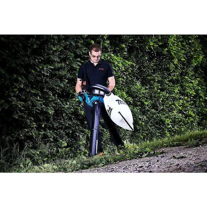 Makita LXT 18V Akku-Laubbläser DUB363PT2V - 18 V, Li-Ionen, 2 Akkus, Blasleistung: 13,4 m³/min - Ein Mann benutzt einen Makita Laubbläser, um Blätter zu entfernen, während er Sicherheitsausrüstung trägt.