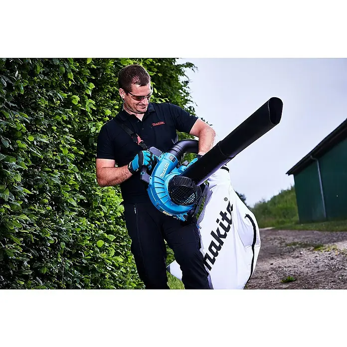 Makita LXT 18V Akku-Laubbläser DUB363PT2V - 18 V, Li-Ionen, 2 Akkus, Blasleistung: 13,4 m³/min - Ein Mann benutzt einen Makita Laubbläser im Freien, umgeben von Grün. Der Laubsauger ist blau und schwarz mit einem weißen Makita-Auffangsack.