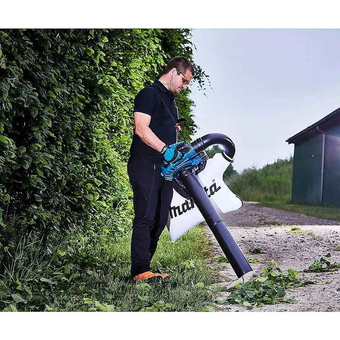 Makita LXT 18V Akku-Laubbläser DUB363PT2V - 18 V, Li-Ionen, 2 Akkus, Blasleistung: 13,4 m³/min - Ein Mann benutzt einen Makita Laubbläser mit Fangsack, um Laub und Abfälle zu beseitigen. Das Gerät ist türkis und schwarz.