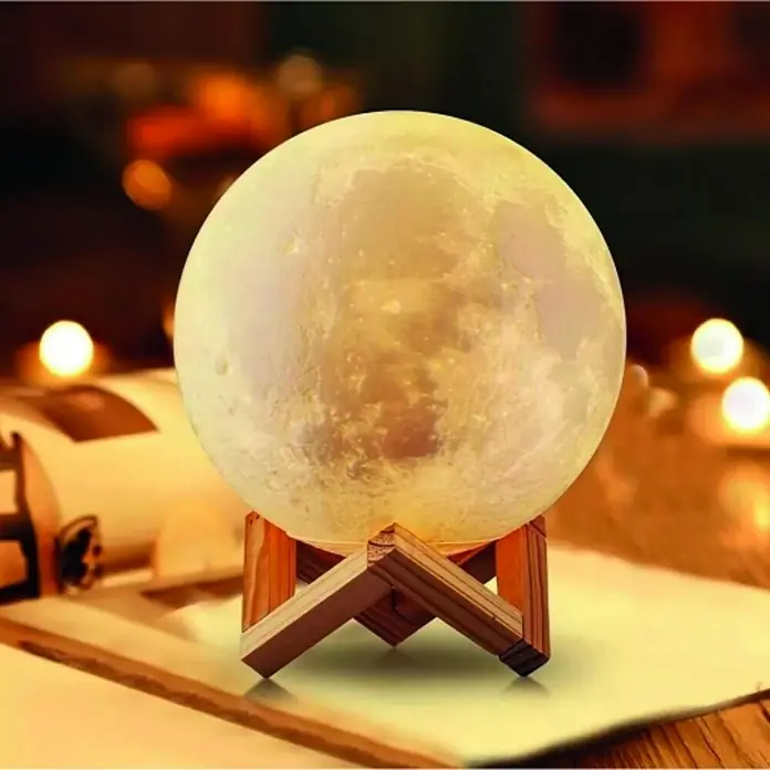 Lámpara de sobremesa Luna - 15 W, Blanco, Blanco frío - Primer plano de una lámpara de luna sobre un soporte de madera, que irradia una luz cálida y suave creando un ambiente acogedor.