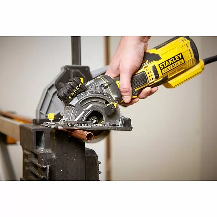 Stanley FatMax Handkreissäge FME380K-QS - 650 W, Durchmesser Sägeblatt: 89 mm, Schnitttiefe bei 90 °: 28,5 mm - Eine gelb-schwarze Stanley Fatmax Kreissäge in einer Hand, die ein Kupferrohr schneidet. Die Säge hat einen silbernen Blattschutz und eine sichtbare Laserführung.