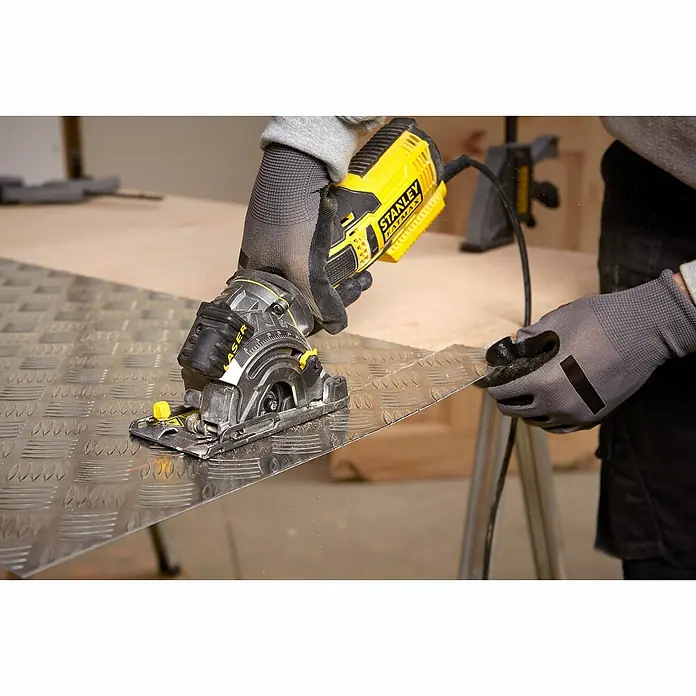Stanley FatMax Handkreissäge FME380K-QS - 650 W, Durchmesser Sägeblatt: 89 mm, Schnitttiefe bei 90 °: 28,5 mm - Nahaufnahme einer Stanley Fatmax Kreissäge in Gelb und Schwarz beim Schneiden einer Metallplatte. Der Bediener trägt Handschuhe.