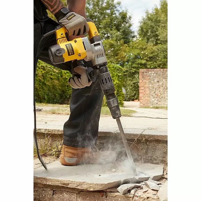 Stanley FatMax Abbruchhammer SFMEH220K-QS - 1.010 W, 8,5 J, SDS-Max-Aufnahme - Eine Person benutzt einen gelben und grauen Stanley FatMax Abbruchhammer, um Beton zu zerbrechen, wodurch Staub entsteht.
