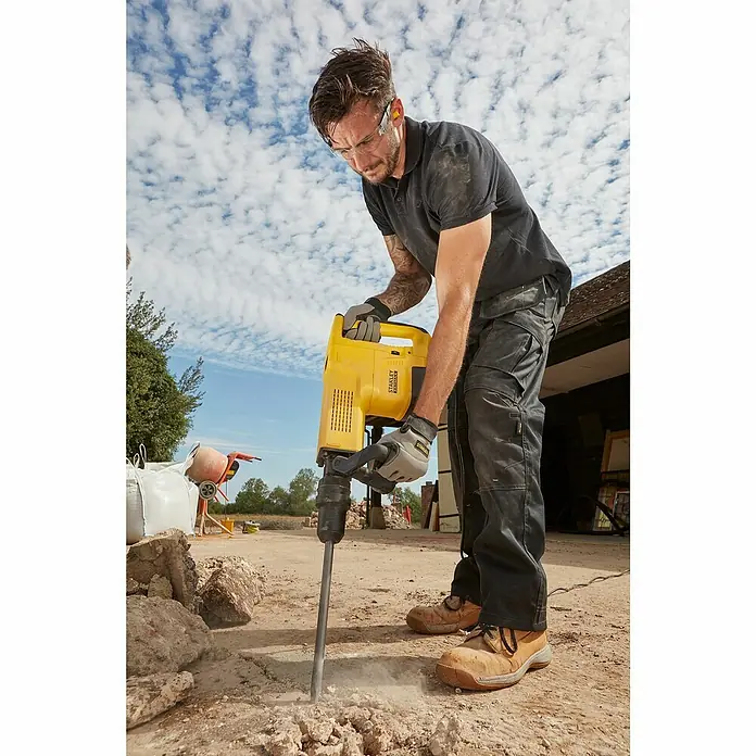 Stanley FatMax Abbruchhammer SFMEH230K-QS - 1.600 W, 15 J, SDS-Max-Aufnahme - Ein Mann benutzt einen Stanley Abbruchhammer, um Beton aufzubrechen, mit einer klaren Betonung auf das Werkzeug und seine Funktion.