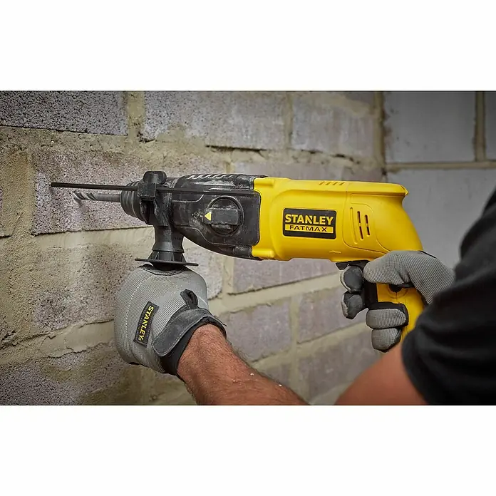 Stanley FatMax Kombihammer SFMEH200K-QS - 750 W, 2,2 J, SDS-Plus-Aufnahme - Ein Mann bohrt mit einer gelben Stanley Fatmax Bohrmaschine ein Loch in eine Ziegelwand.