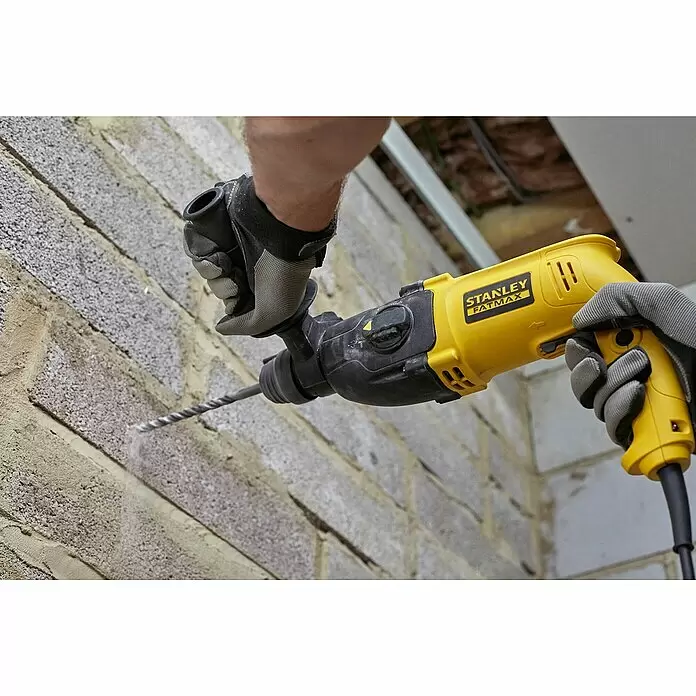 Stanley FatMax Kombihammer SFMEH200K-QS - 750 W, 2,2 J, SDS-Plus-Aufnahme - Gelber und schwarzer Stanley Fatmax Bohrhammer in Gebrauch, bohrt in eine Ziegelwand, gehalten von behandschuhten Händen.