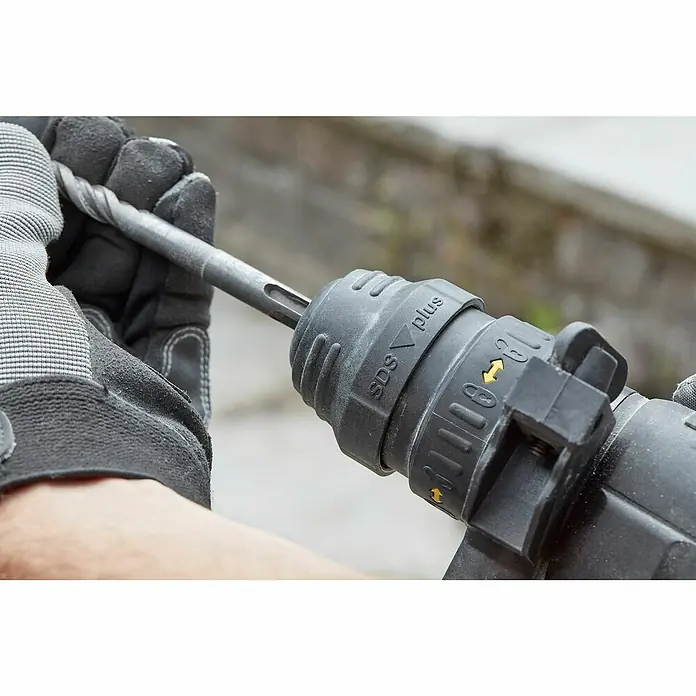 Stanley FatMax Kombihammer SFMEH210K-QS - 800 W, 2,4 J, SDS-Plus-Aufnahme - Nahaufnahme einer SDS Plus Bohrmaschine mit eingesetztem Bohrer und einer Hand mit Arbeitshandschuh.