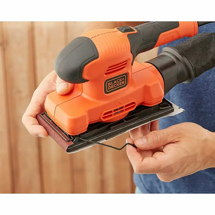 Black+Decker Elektro-Schwingschleifer BEW220-QS - 150 W - Nahaufnahme eines Black+Decker-Schleifgeräts, das von einer Person bedient wird. Präzision und Komfort vereint in einem Werkzeug.