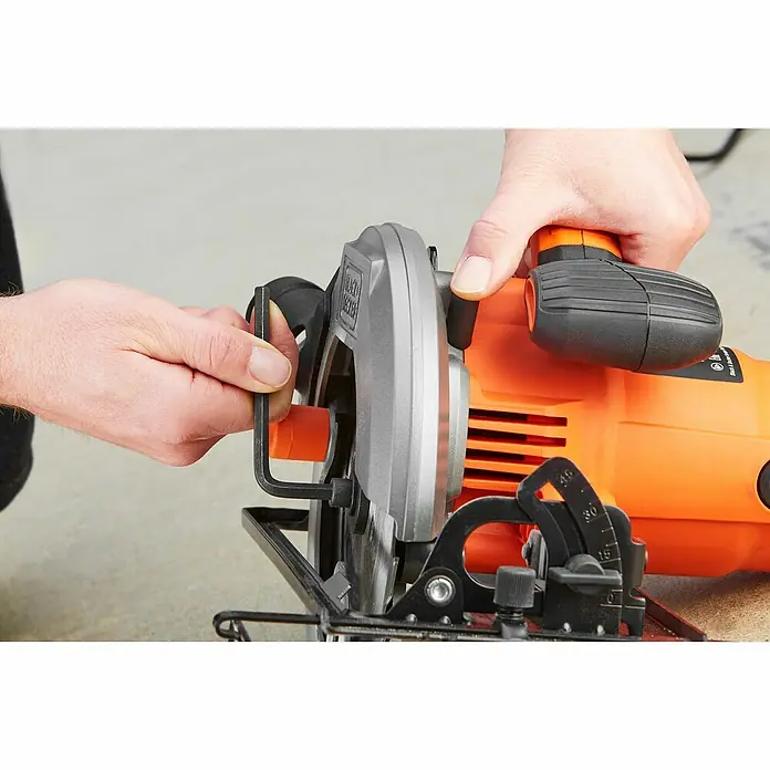 Black+Decker Handkreissäge CS1550-QS - 1.500 W, Durchmesser Sägeblatt: 190 mm, Schnitttiefe bei 90 °: 66 mm - Nahaufnahme einer Black+Decker Kreissäge in Orange und Grau, die von zwei Händen bedient wird.